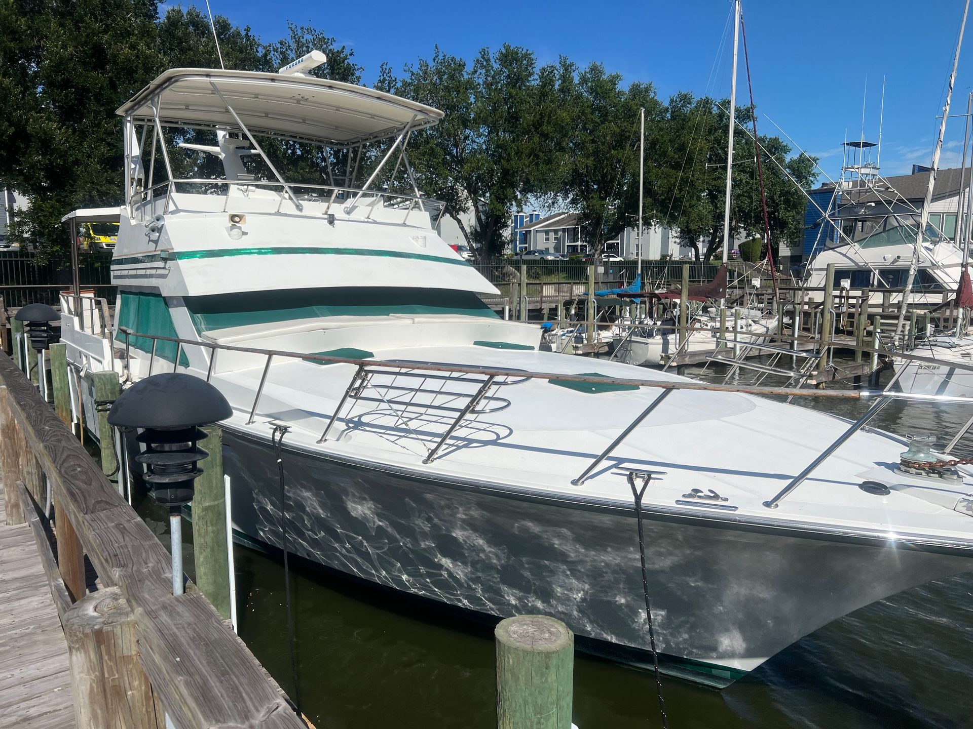 A large white boat is docked at a marina.