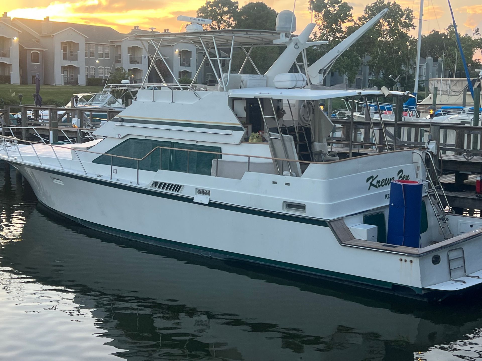 A large white boat is docked in a marina at sunset.