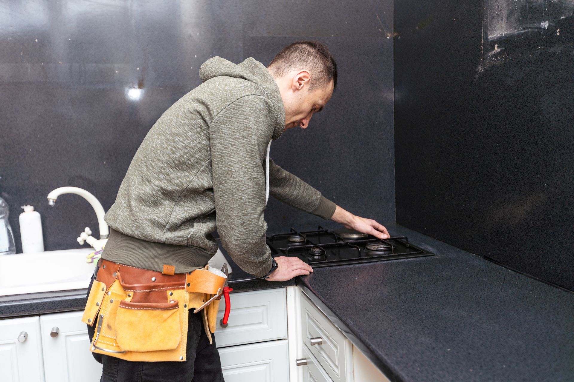 The technician adjusts the built in gas stove in a modern kitchen workspace.