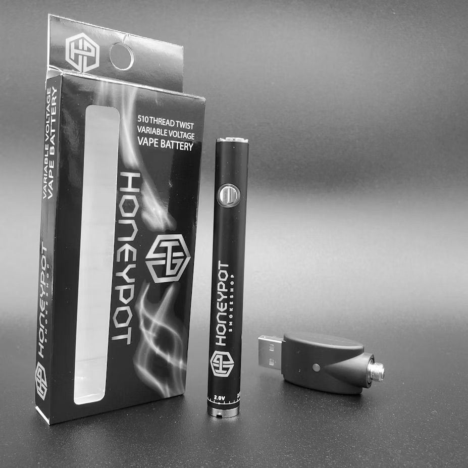 A black Honeypot vape pen, its packaging box, and a USB charging attachment displayed against a neutral background.