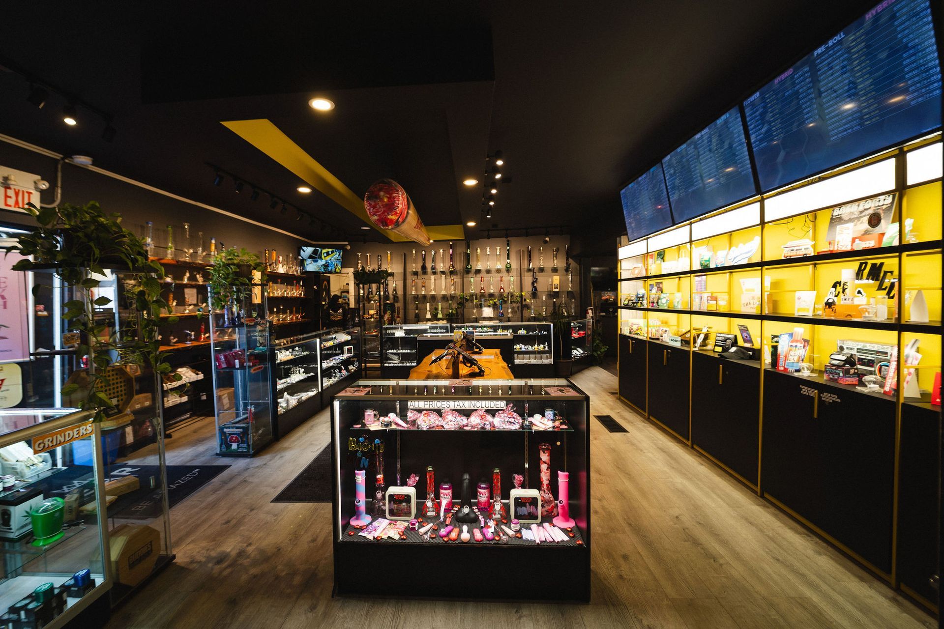 An interior view of a modern smoke shop featuring glass display cases, shelves with smoking accessories, and wood floors.