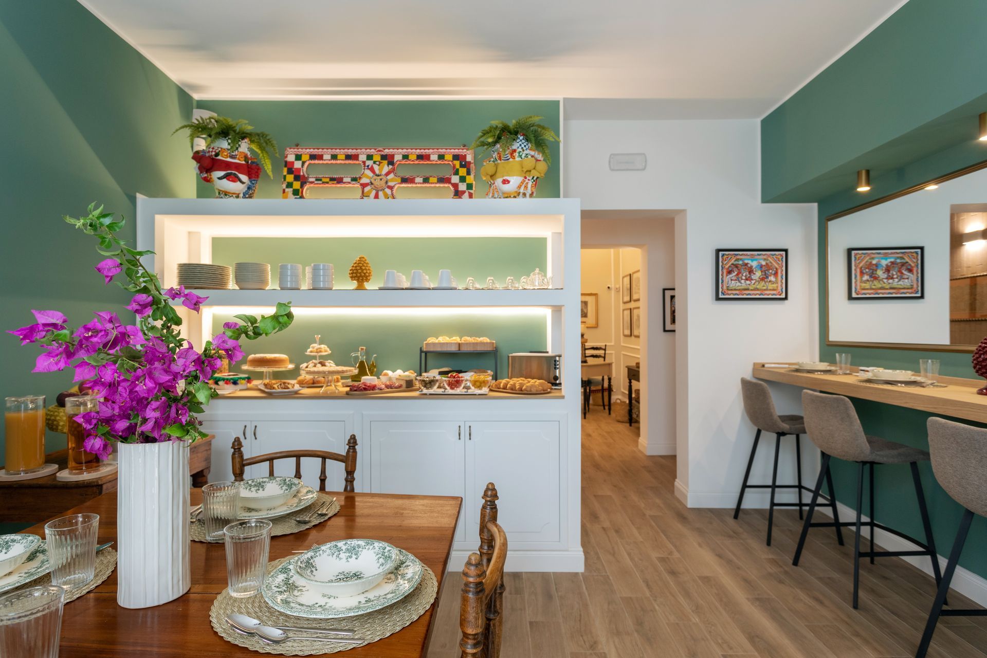 Colazione a buffet in una sala con tavolo apparecchiato e bancone con sgabelli.