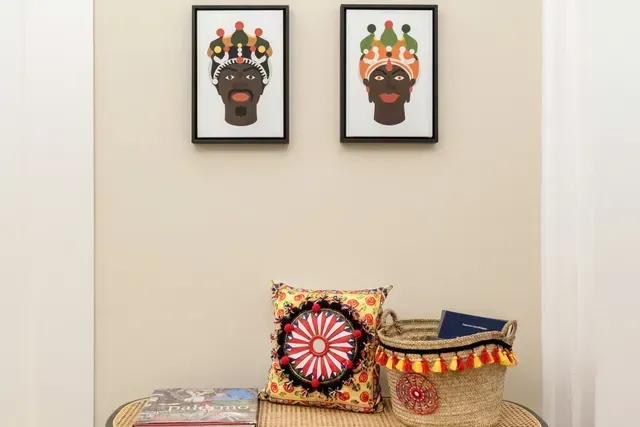 Due stampe artistiche incorniciate sopra una panca con un cuscino, un cestino e dei libri.