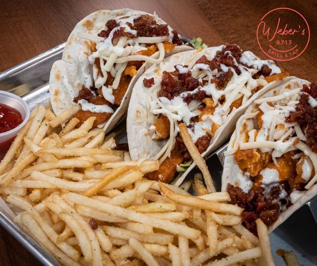 A tray of tacos and french fries on a table.