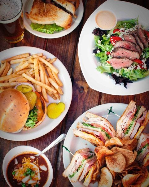 A table topped with plates of food including sandwiches and french fries