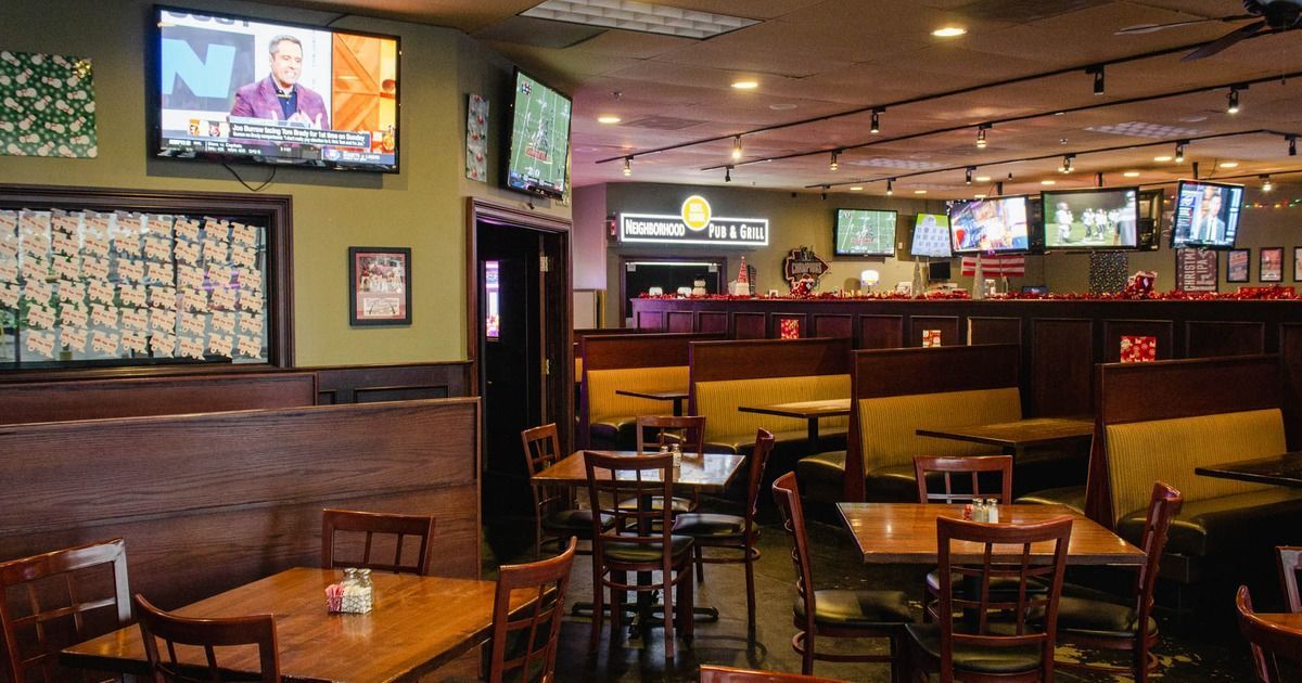 A restaurant with tables and chairs and televisions on the wall.