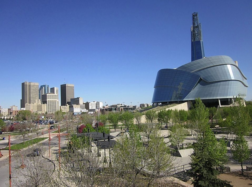 Modern glass tower and city skyline beside a park on a clear day