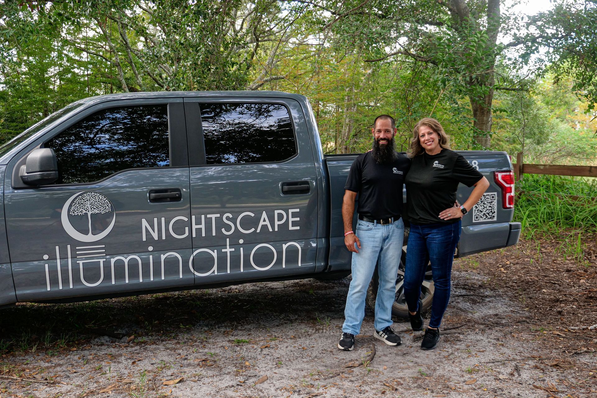Two people standing by a gray truck with the Nightscape illumination logo.