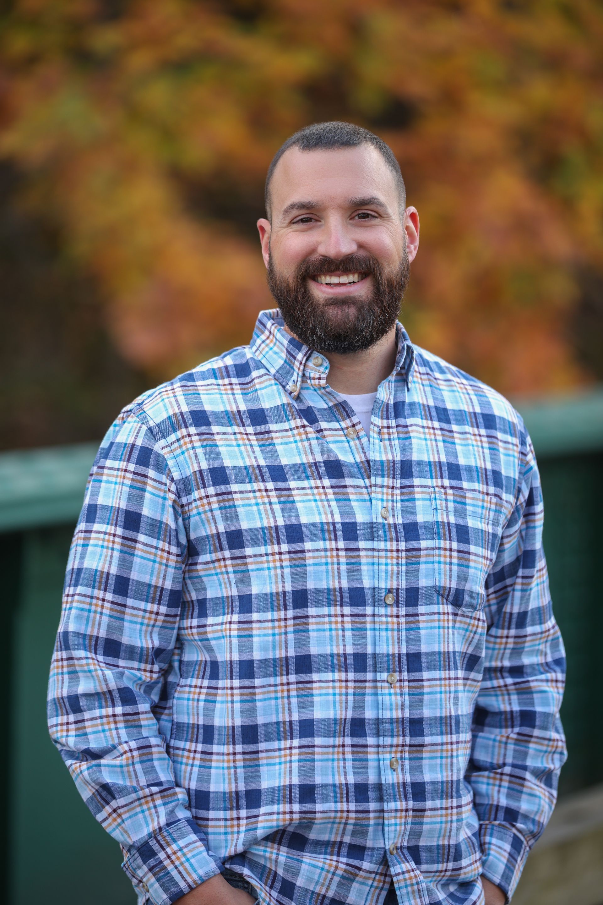 Caricature of a man with a beard, wearing blue outfit, smiling, and carrying a bag.