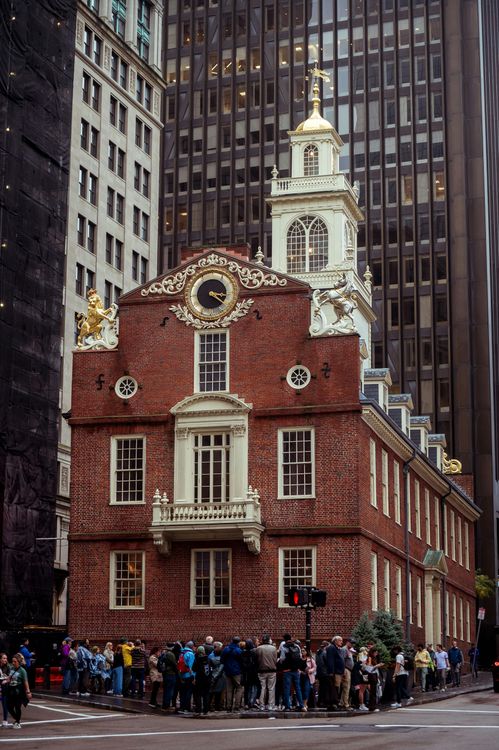 Old State House, Boston, brick building with clock tower, surrounded by modern skyscrapers and a crowd of people.