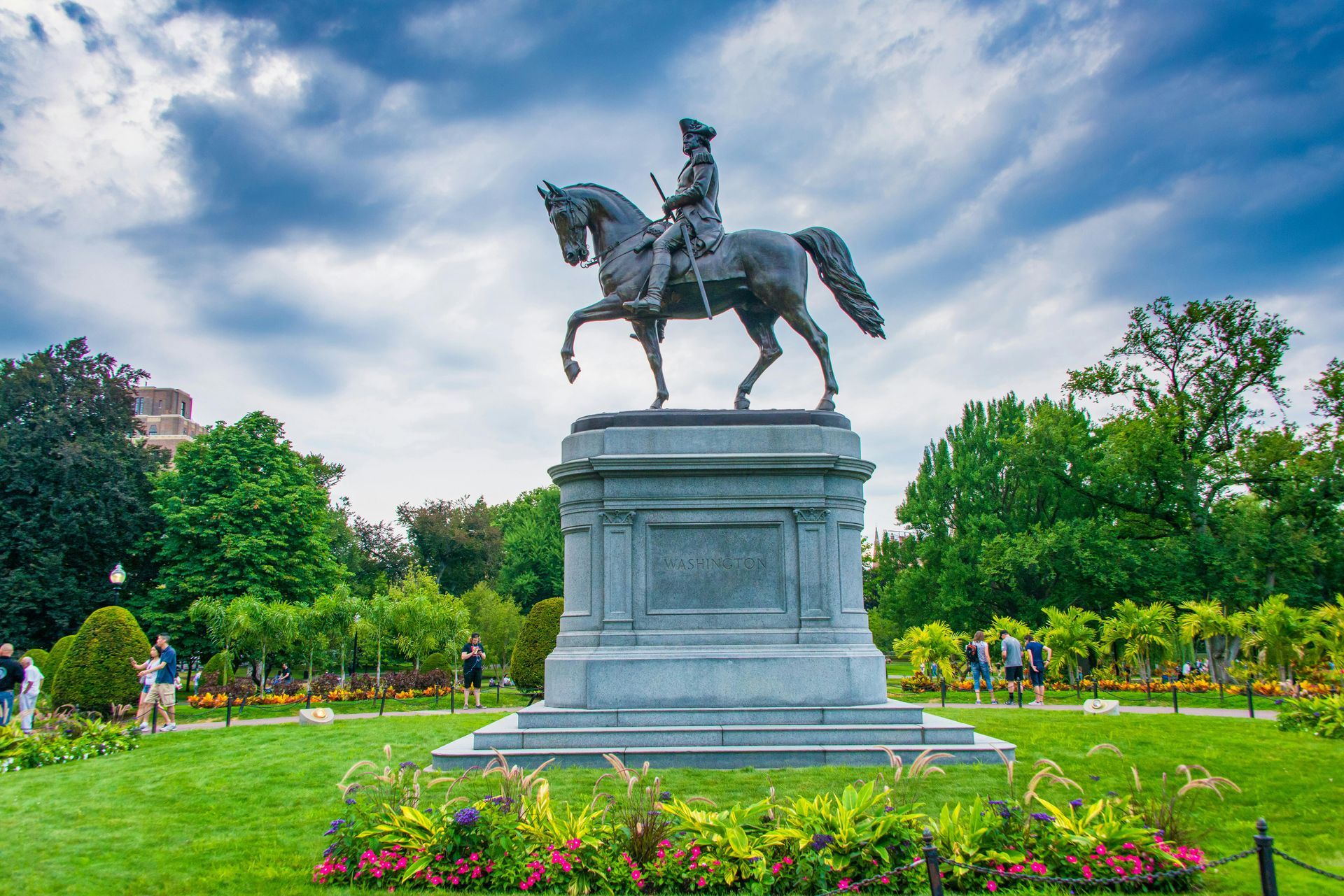 Statue of George Washington on horseback in Boston Public Garden, surrounded by greenery and flowers.