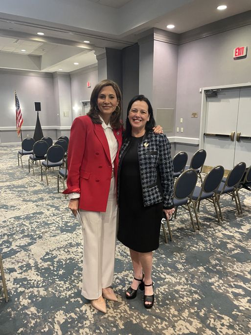 Two women are posing for a picture in a room with chairs