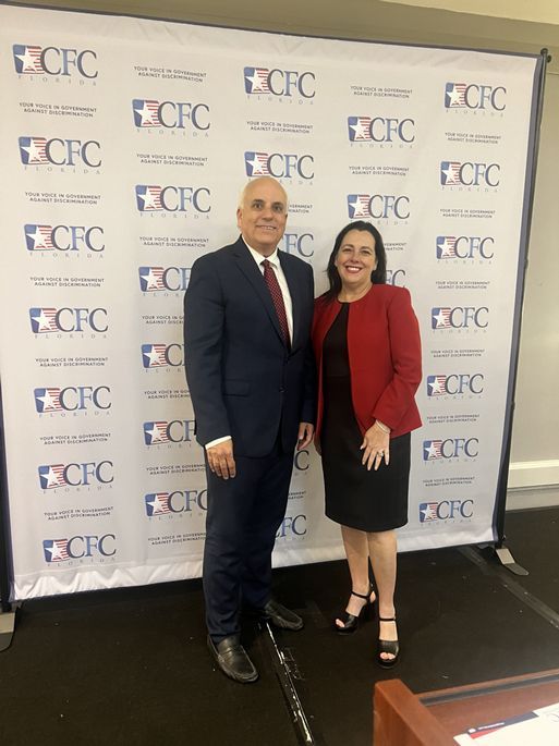 A man and a woman standing in front of a CFC backdrop