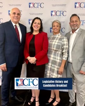 A group of people standing in front of a wall that says legislative victory and candidates breakfast