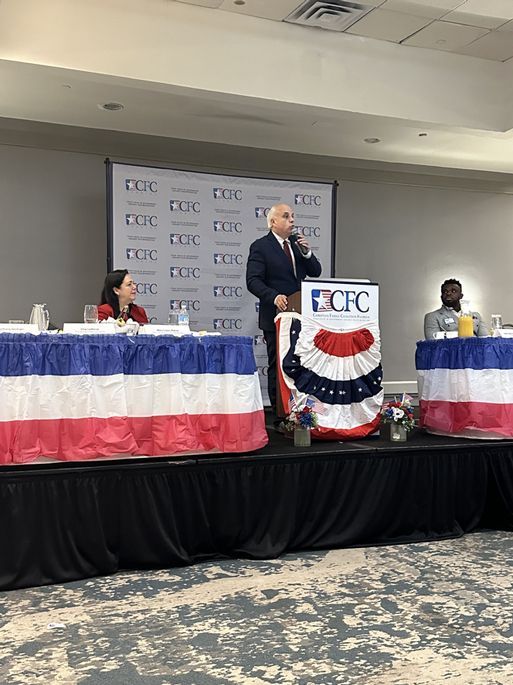 A man is standing at a podium giving a speech at a conference