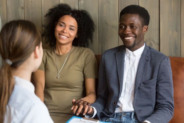 A man and a woman are sitting on a couch talking to a woman