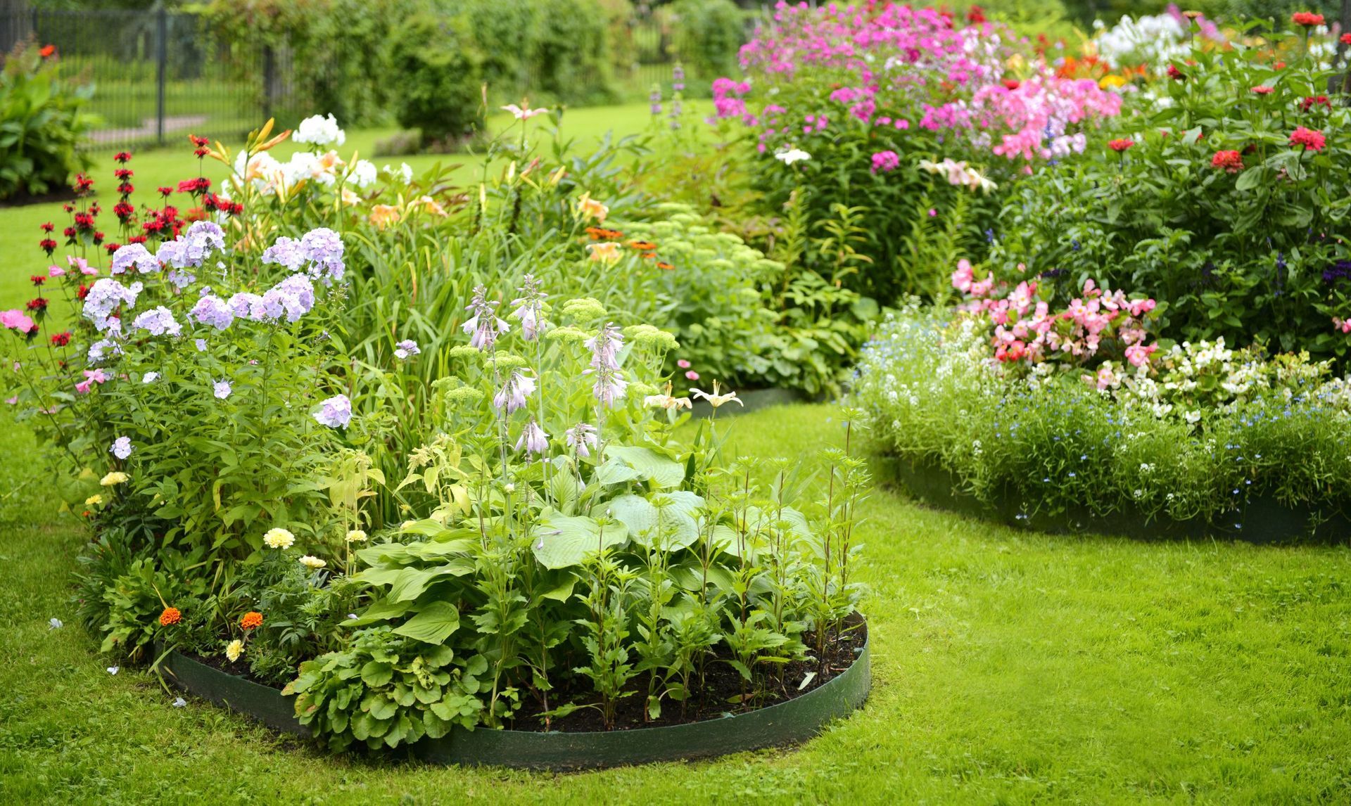 Lush garden beds with colorful flowers and green grass. Lush garden beds with colorful flowers and green grass.