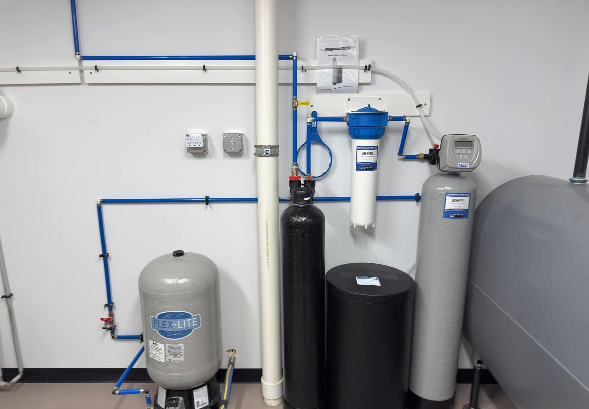 Young man in workwear using pliers while installing water filtration system