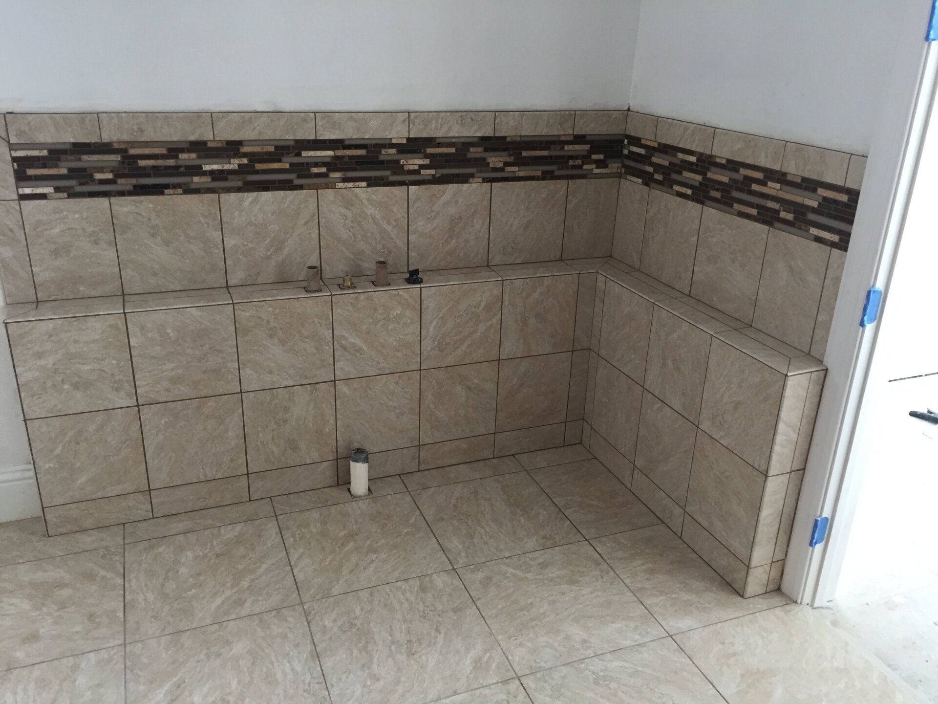 Bathroom with tiled walls and floor in beige, with a dark mosaic accent border.