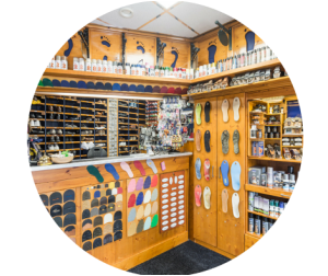 In een schoenenwinkel worden diverse schoenzolen en producten tentoongesteld. Houten planken en toonbank.