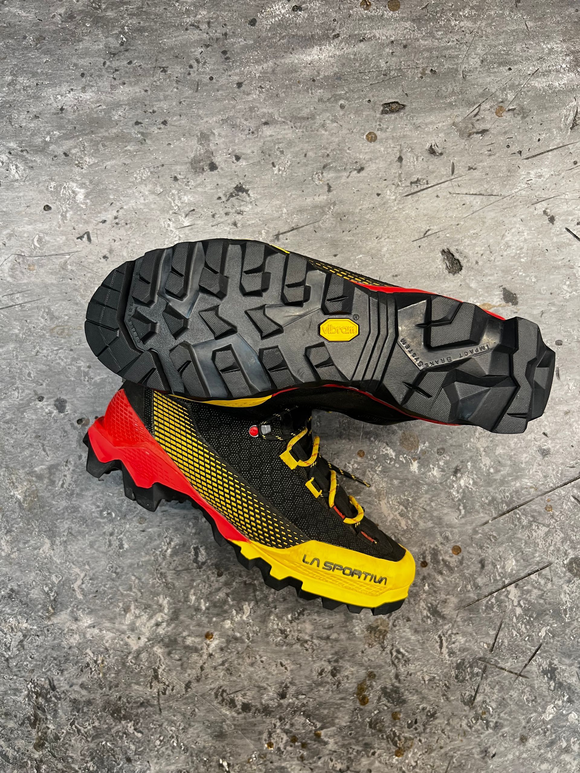 Een paar geel-zwarte klimschoenen van La Sportiva op een grijze ondergrond, waarbij de zolen en zijkanten zichtbaar zijn.