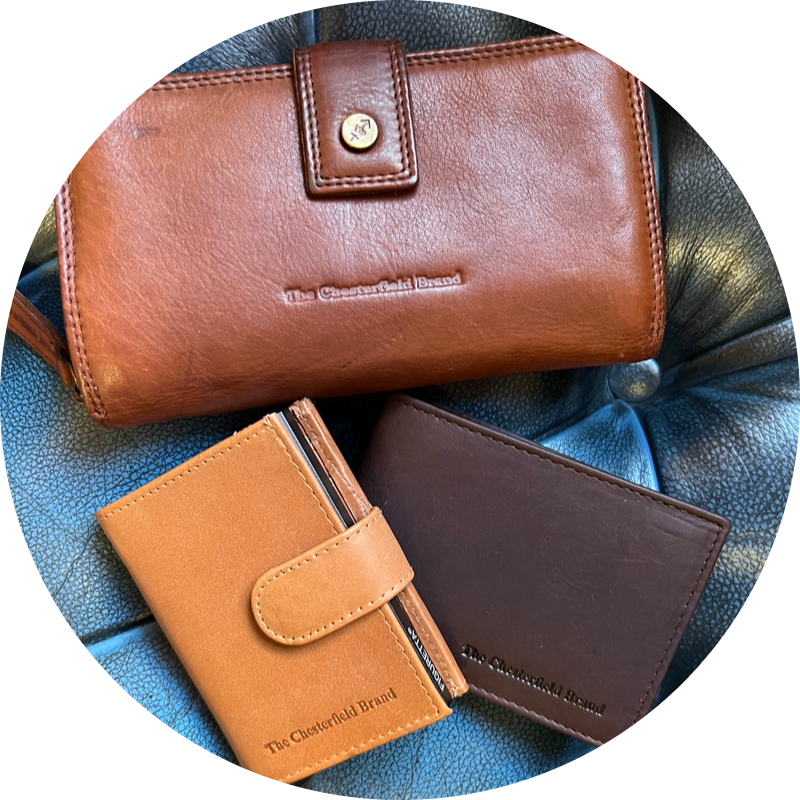 Drie leren portemonnees in verschillende kleuren op een blauw oppervlak.