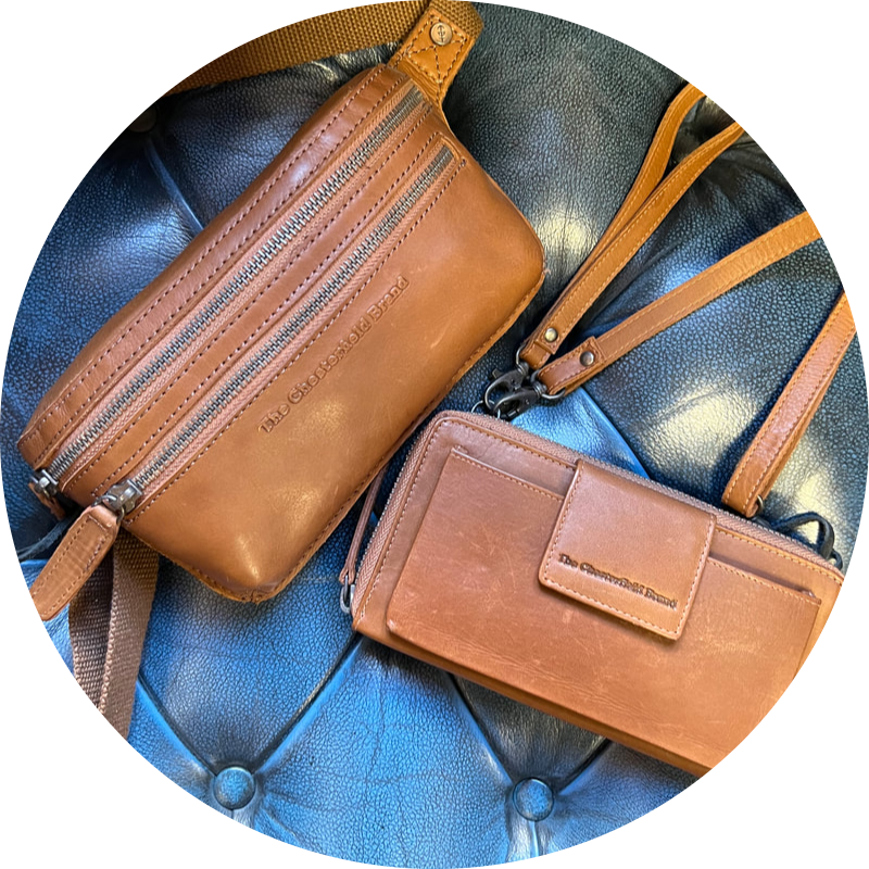 Twee bruine leren tassen met een blauw geknoopt oppervlak, één crossbody-model en één portemonnee-model met een polsbandje.