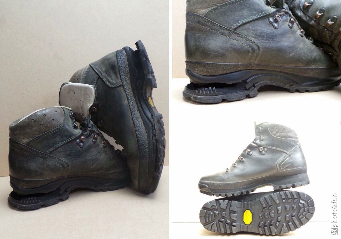 Een paar versleten zwarte wandelschoenen met losse zolen. Bruine achtergrond.
