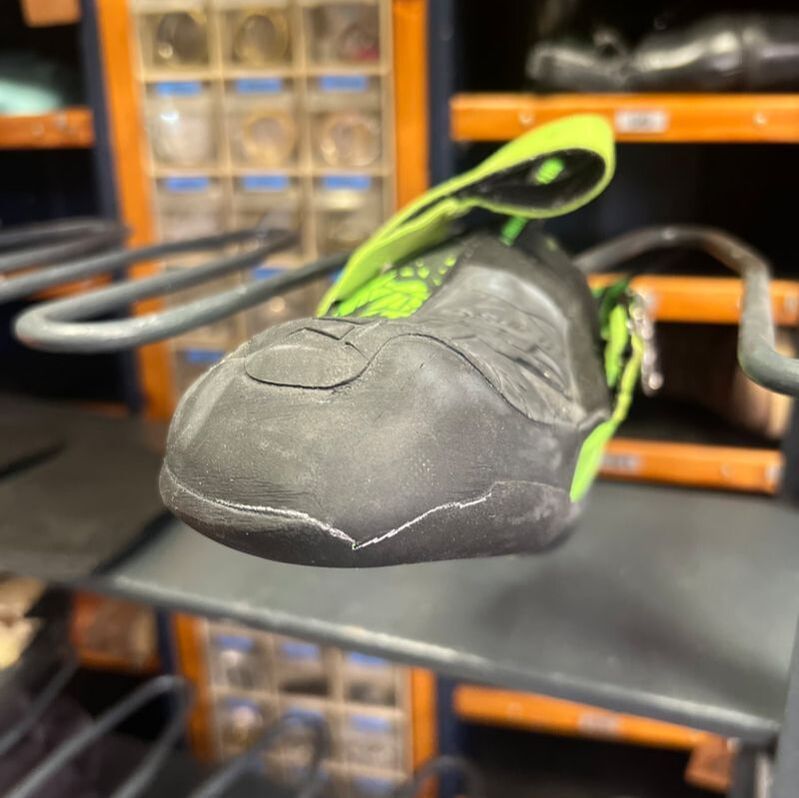 Zwarte en groene klimschoenen op een rek in een winkel.