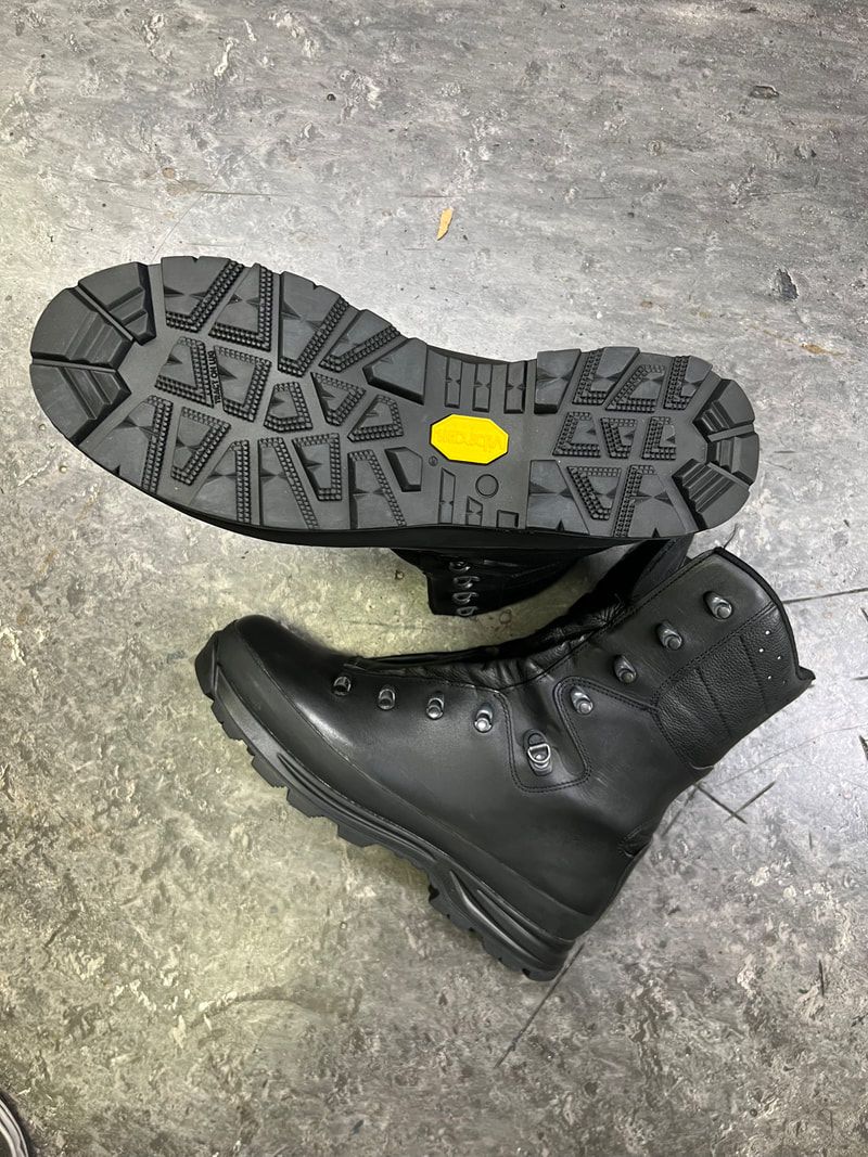 Zwarte wandelschoenen met Vibram-zool op een grijze ondergrond.