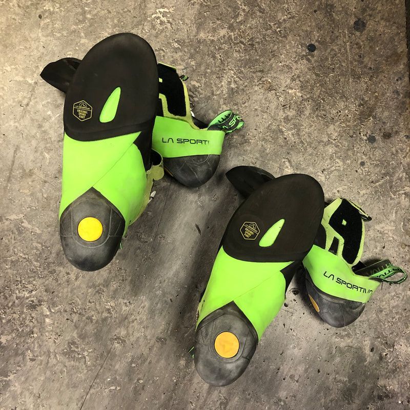 Een paar felgroene en zwarte klimschoenen van La Sportiva op een betonnen vloer.