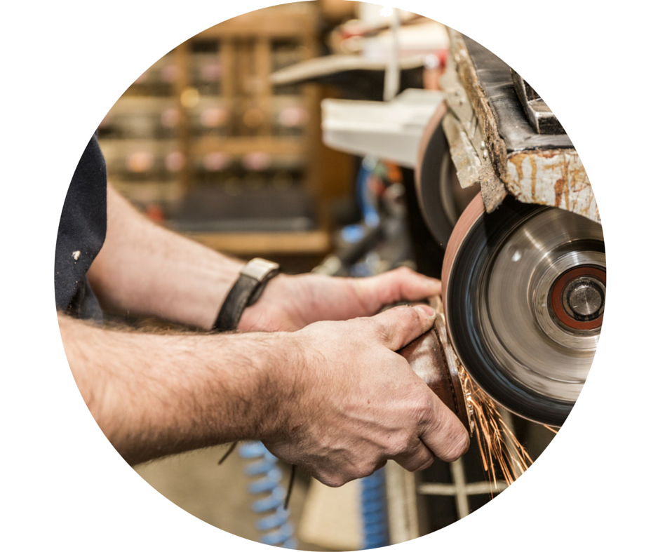 Iemand gebruikt een slijpmachine en creëert vonken, waarschijnlijk om gereedschap te slijpen in een werkplaats.