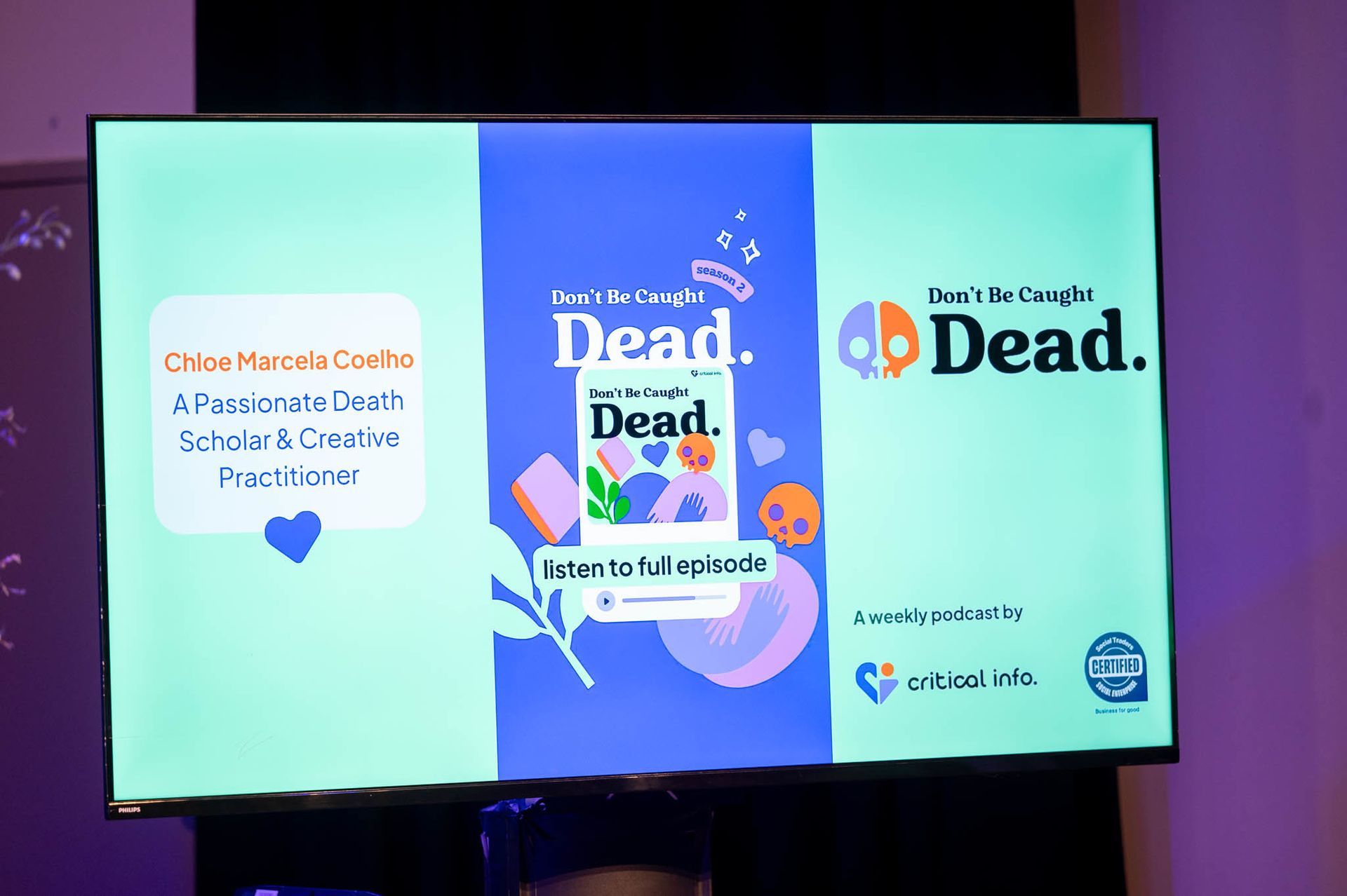 Screen advertising the Don't Be Caught Dead podcast at the Critical Info Launch event.