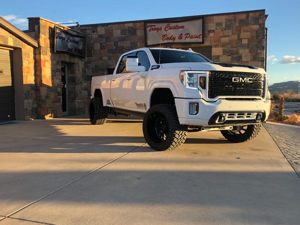 A white gmc truck is parked in front of a building.