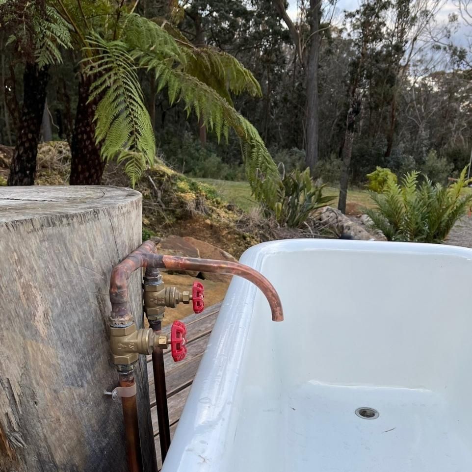 A Bathtub with A Faucet Attached to It Is Outside in The Woods — Bowral Bathrooms in Exeter, NSW