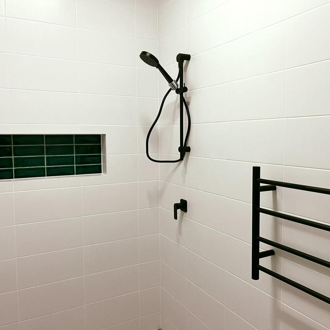 A Bathroom with White Tiles, a Shower Head and A Towel Rack — Bowral Bathrooms in Exeter, NSW