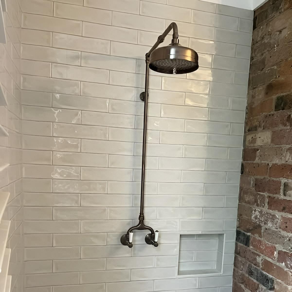 A Shower Head Is Hanging from A Brick Wall in A Bathroom — Bowral Bathrooms in Exeter, NSW