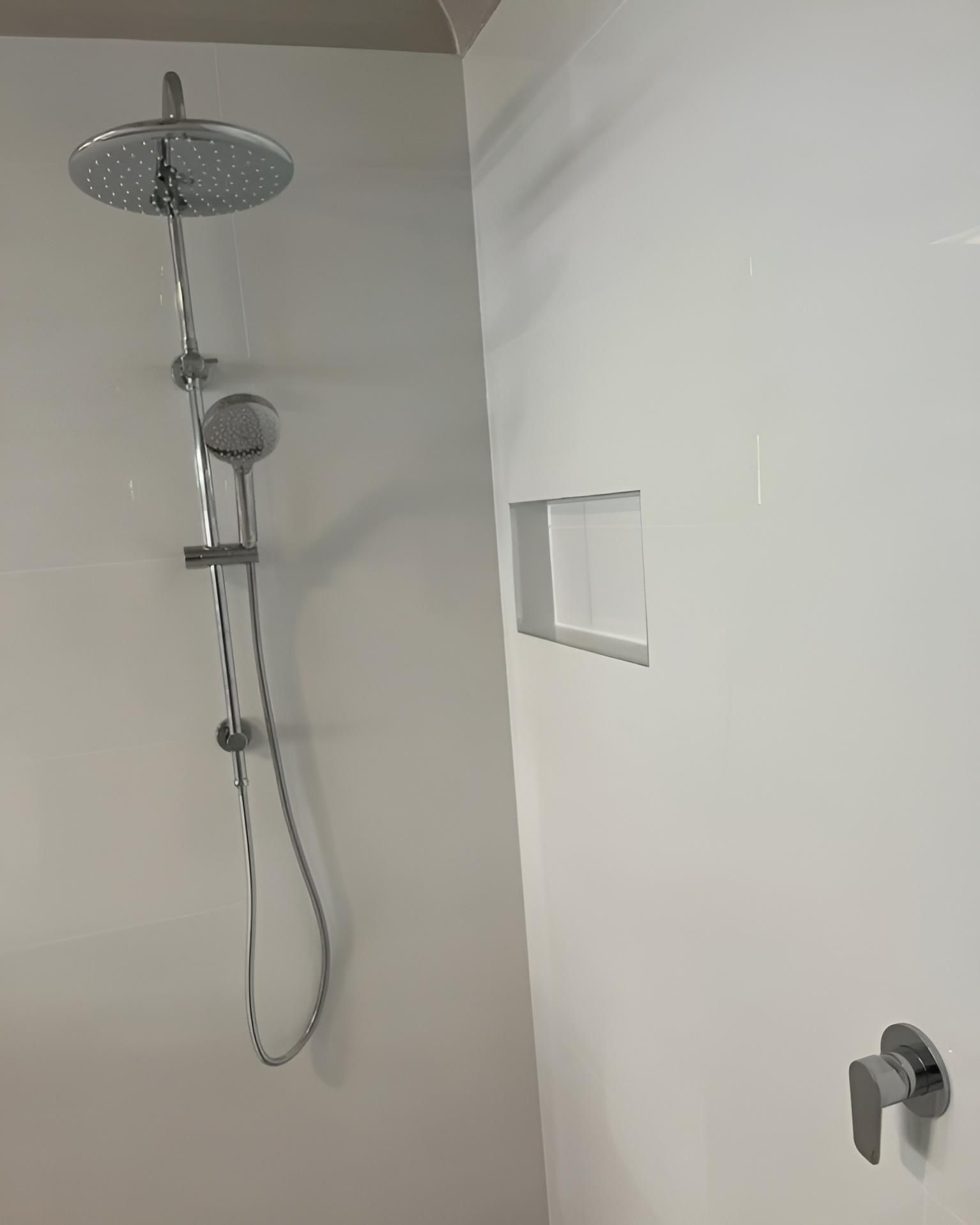 A Shower Head Is Hanging from A White Wall in A Bathroom — Bowral Bathrooms in Exeter, NSW