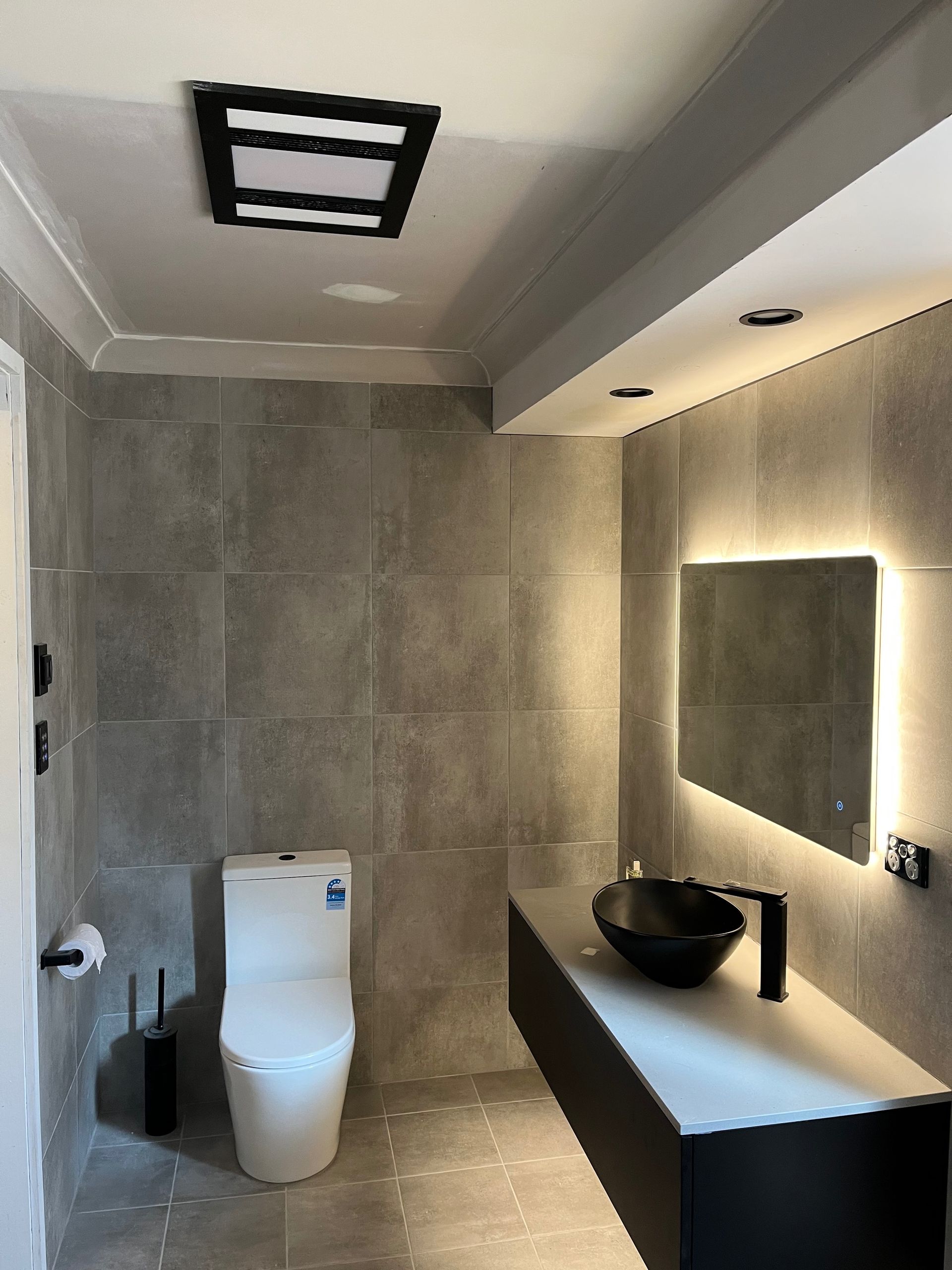 A bathroom with a toilet , sink and mirror — Bowral Bathrooms in Exeter, NSW