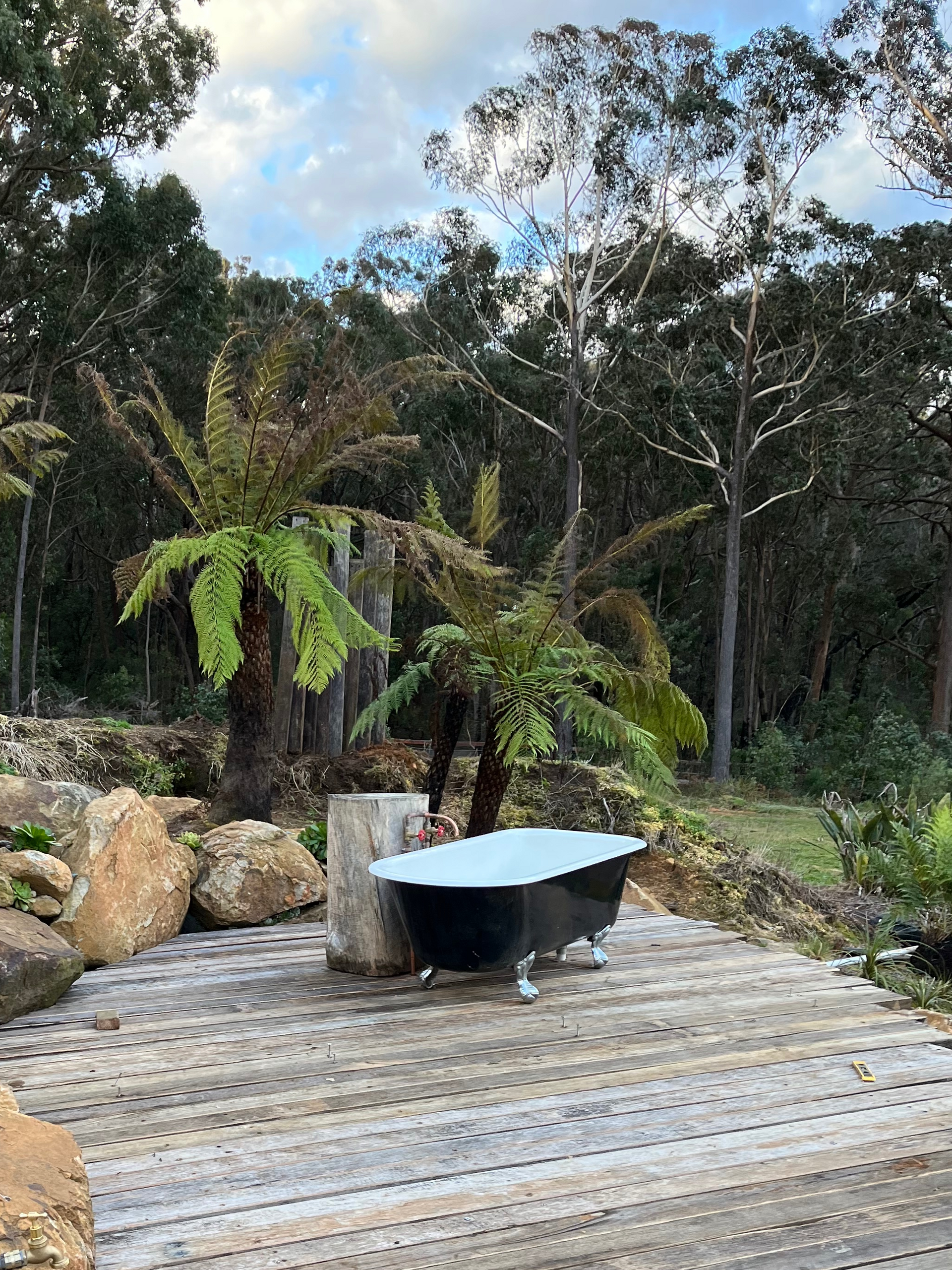A bathtub is sitting on a wooden deck in the middle of a forest — Bowral Bathrooms in Exeter, NSW