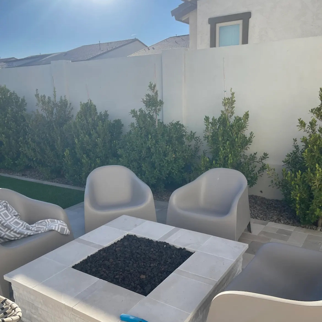 A patio with chairs and a table with a fire pit in the middle