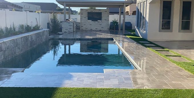 A large swimming pool is in the backyard of a house.