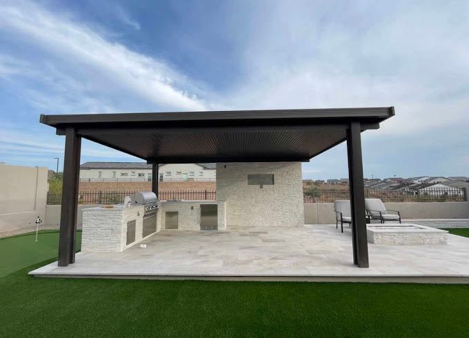 A patio with a pergola and a grill in the backyard.