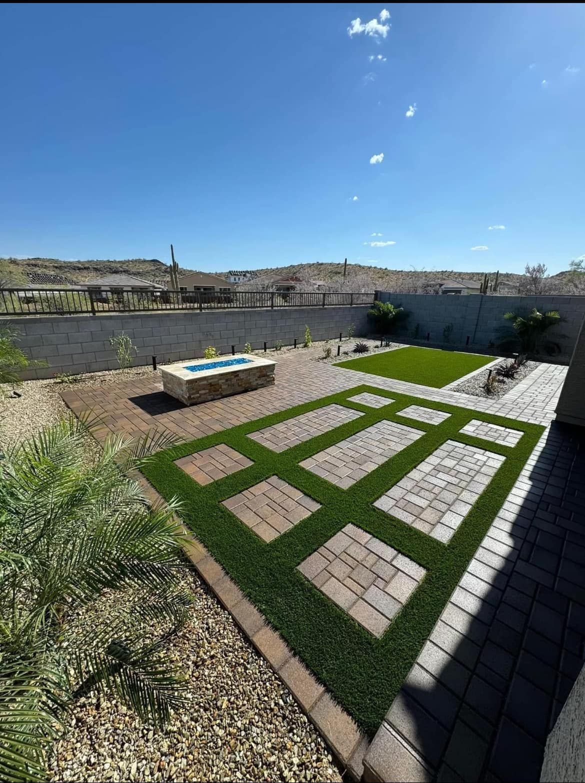 A backyard with a fire pit and a brick walkway.