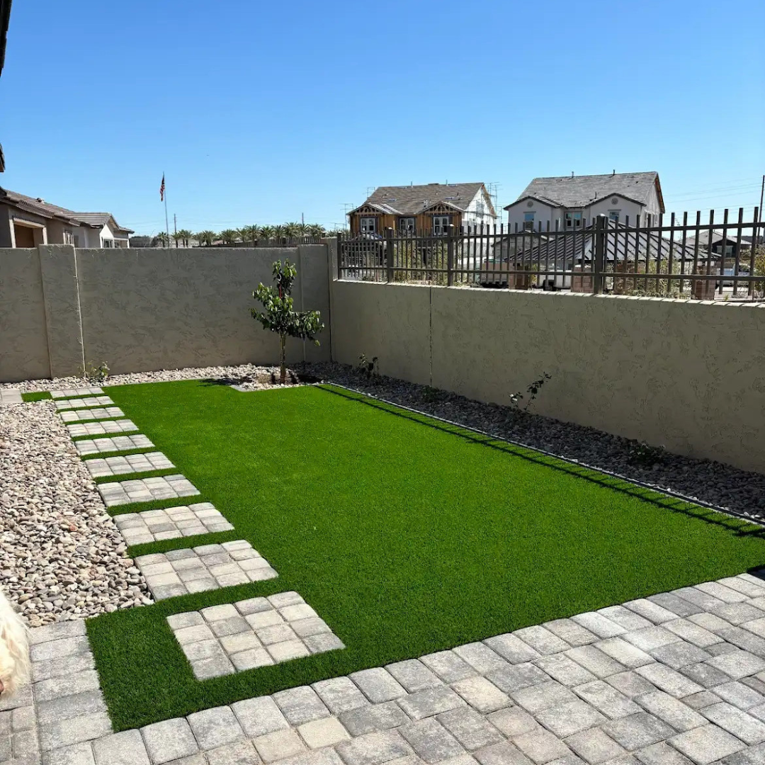 A backyard with a brick walkway leading to a grassy area.