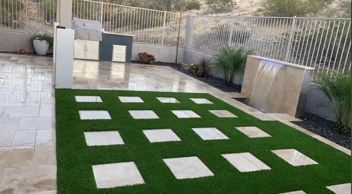 A lawn with squares on it and a waterfall in the background.
