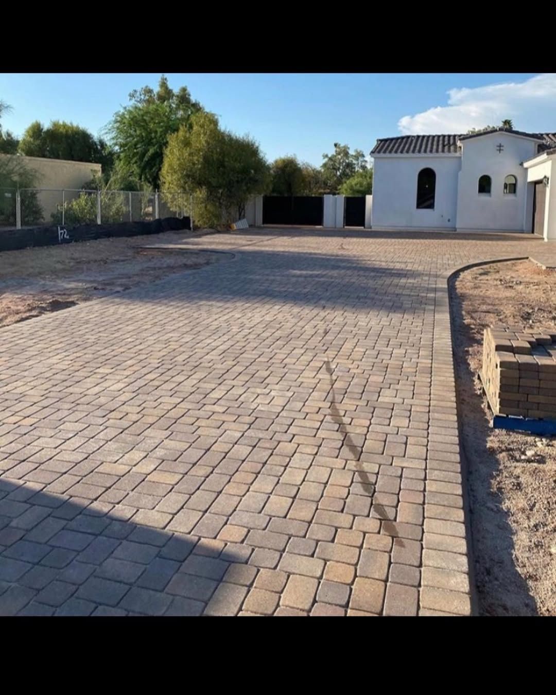 A brick driveway with a white house in the background
