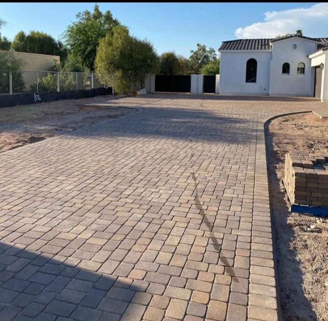 A brick driveway with a white house in the background
