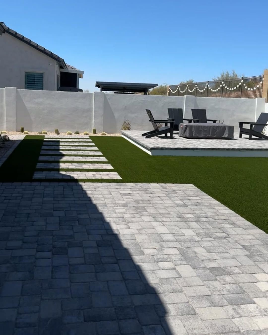 A backyard with a brick walkway leading to a fire pit