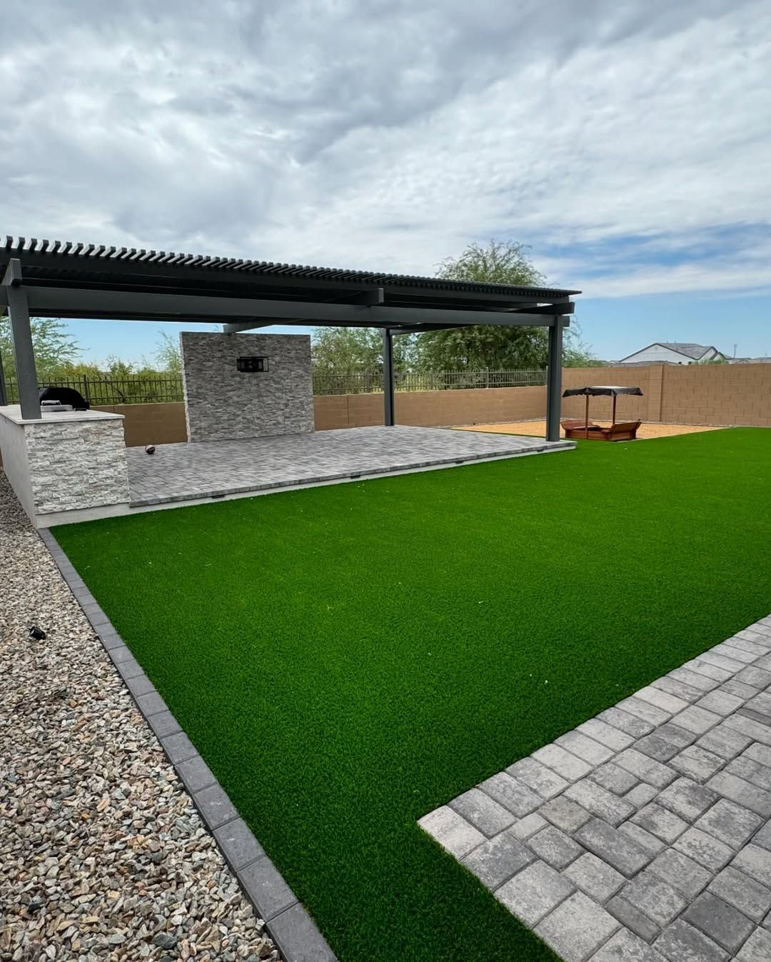 A backyard with a lot of grass and a stone wall